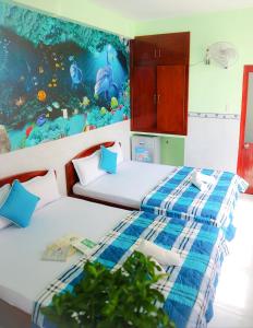 Thai Quang Hotel في فنغ تاو: سريرين في غرفة مع لوحة على الحائط