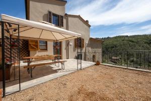 un patio con mesa y sombrilla en Podere del Ciacchi Among Tuscany Greenery - Happy Rentals, en Montieri
