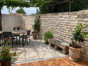 eine Terrasse mit einem Tisch, Stühlen und einer Steinmauer in der Unterkunft La Jas, demeure climatisée au charme gardois. in Nages-et-Solorgues