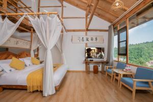 昆明春庄山隐民宿 في كونمينغ: غرفة نوم بسرير مظلة وطاولة وكراسي