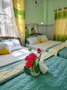 Thai Quang Hotel في فنغ تاو: مزهرية مع ورود حمراء على سرير