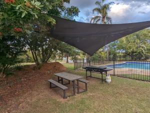 a picnic table and a bench in front of a fence at Y Motels Gympie in Gympie