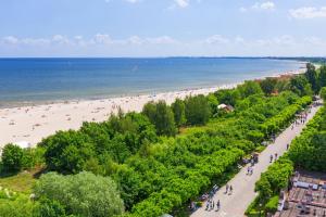 a beach with people walking on the sand and the water at Cappuccino - Park Reagana in Gdańsk