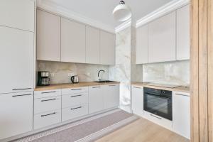 a white kitchen with white cabinets and appliances at Cappuccino - Park Reagana in Gdańsk