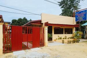 a red gate in front of a building at Shandy's Transient House in Palompon