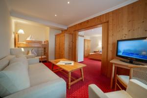 ein Wohnzimmer mit einem weißen Sofa und einem TV in der Unterkunft Hotel Alpenblick in Filzmoos