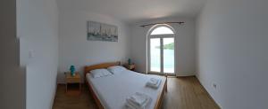 une chambre avec un grand lit et une fenêtre dans l'établissement Mljet Sunset Apartments, à Pomena