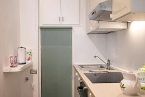 a white kitchen with a sink and a refrigerator at Casa Bouganville - St. Peter Romantic Apartment in Rome