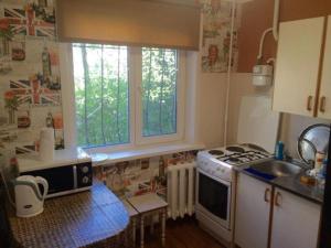 a kitchen with a stove and a sink and two windows at Новый Люкс в центре города по Алиханова in Karagandy