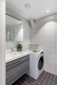 uma casa de banho com uma máquina de lavar roupa e um lavatório em 1-Roms toppleilighet på tangen/bystranda em Kristiansand
