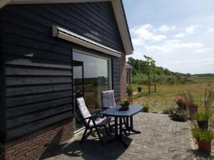 un patio avec une table et des chaises à côté d'un bâtiment dans l'établissement De Bloemenkwekerij, à Egmond-Binnen