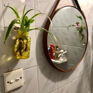 a mirror on a wall with a vase with a plant at Mika Homestay Simple & Cozy in Hanoi