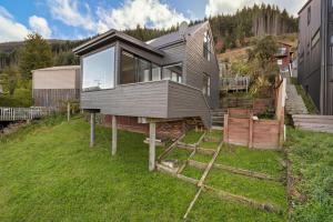 uma casa no topo de uma colina relvada em Remarkable Alpine Holiday Home em Queenstown