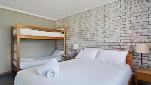 a bedroom with two bunk beds and a brick wall at Lawlers 29 in Mount Hotham