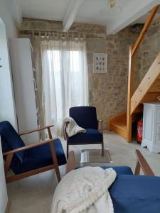 a living room with two blue chairs and a staircase at La petite maison bleue in Mouret