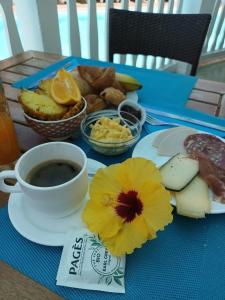 une table bleue avec une assiette de nourriture et une tasse de café dans l'établissement Hôtel Exsel Ermitage, à Saint-Gilles les Bains