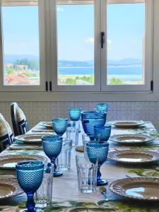 a table with blue glasses and plates on it at Piso familiar cerca de playa in Pobra do Caramiñal