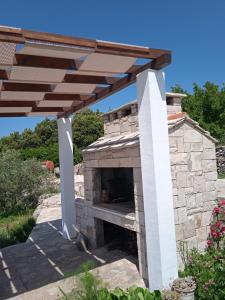 an outdoor pizza oven with a wooden roof at Holiday Home Zule in Žrnovo