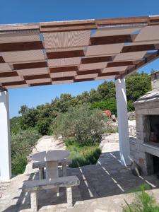 a picnic table and a bench under a wooden pergola at Holiday Home Zule in Žrnovo