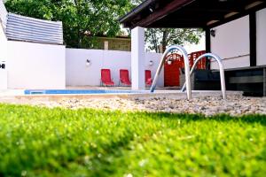 a playground with two red chairs in a yard at Holiday Home Mumy in Gostinjac
