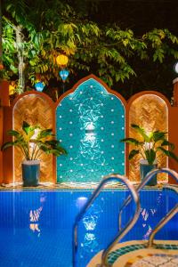 a swimming pool with a blue tile wall and plants at Boutique Villa in Hoi An Oldtown in Hoi An