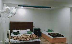 een slaapkamer met 2 bedden en een ventilator aan de muur bij Hotel saspolo skardu in Skardu