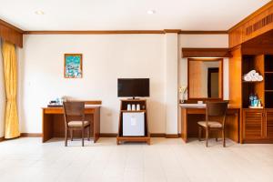 - un salon avec des chaises, une télévision et un bureau dans l'établissement Tony Resort, à Patong Beach