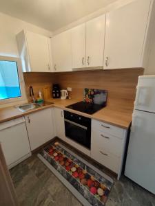 een keuken met witte kasten, een wastafel en een oven bij Apartments Ankica Blue in Peroj