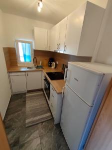 a kitchen with white cabinets and a white refrigerator at Apartments Ankica Blue in Peroj