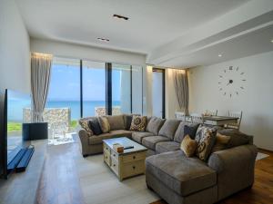 a living room with a couch and a clock on the wall at Onna Resort 海まで徒歩0秒 最大12名宿泊可 オーシャンビュー貸切ヴィラ in Nago