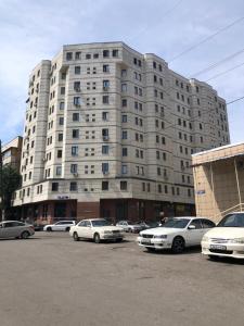 a large building with cars parked in a parking lot at Уютная квартира в центре города in Almaty