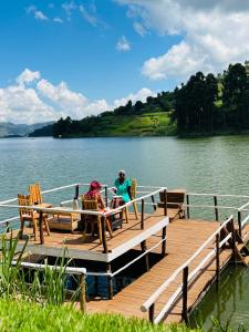 two people sitting on a dock on a lake at Lake Bunyonyi Rock Resort in Kabale
