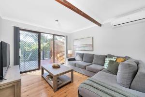 a living room with a couch and a tv at Fields of Green by Experience Jervis Bay in Vincentia