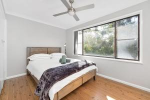 a bedroom with a bed and a large window at Fields of Green by Experience Jervis Bay in Vincentia
