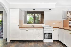 a kitchen with white cabinets and a window at Fields of Green by Experience Jervis Bay in Vincentia