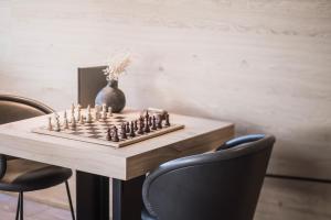 ein Schachbrett auf einem Tisch mit Stühlen und einer Vase in der Unterkunft Hotel Winkler Sport & Spa Resort in St. Lorenzen