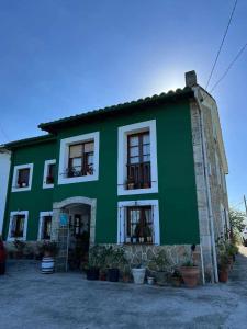 a green and white building with plants in front of it at Casa Rural La Pereda in Noriega