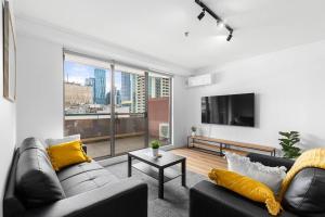 2-Bedroom Apartment in Paris End of Melbourne CBD في ملبورن: غرفة معيشة بها كنبتين ونافذة كبيرة
