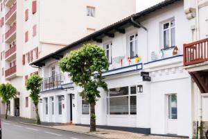 a white building with a tree in the street at Urban Style Biarritz Le Relais in Biarritz