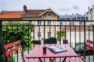 une table rouge avec un livre sur un balcon dans l'établissement Urban Style Biarritz Le Relais, à Biarritz
