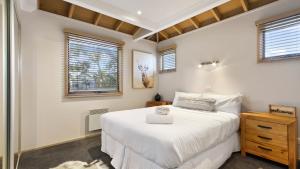 a bedroom with a large white bed and windows at Altitude in Dinner Plain