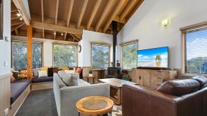 a living room with couches and a flat screen tv at Altitude in Dinner Plain