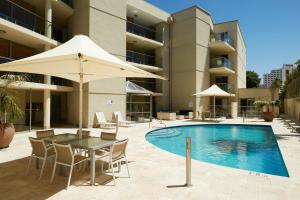 una piscina con mesa, sillas y sombrilla en Seashells Scarborough, en Perth