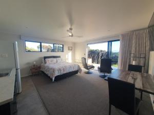 a bedroom with a bed and a table and chairs at Makuri Bay Hideaway in Purerua