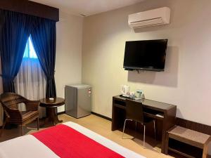 a hotel room with a bed and a desk and a television at Eight Days Boutique Hotel - Impian Emas in Skudai