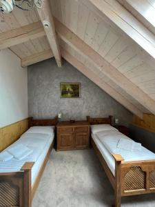 two beds in a attic room with wooden ceilings at Vila Liberta in Poprad
