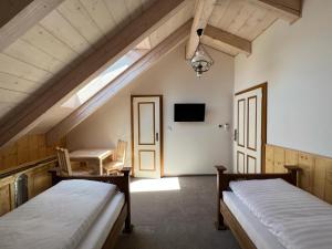 a attic room with two beds and a table at Vila Liberta in Poprad