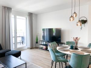 ein Wohnzimmer mit einem Tisch und Stühlen sowie einem TV in der Unterkunft E&K living - 6 pers - design apartment - fair - congress - parking in Augsburg
