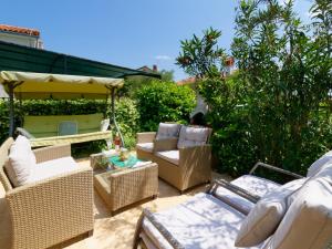 eine Terrasse mit Korbstühlen und einem Sonnenschirm in der Unterkunft Holiday Home Nevena in Buje
