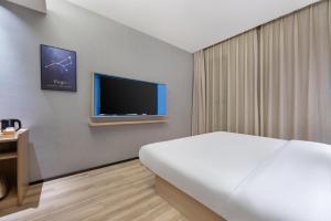 a hotel room with a bed and a flat screen tv at 星程西安钟楼回民街酒店 in Xi'an